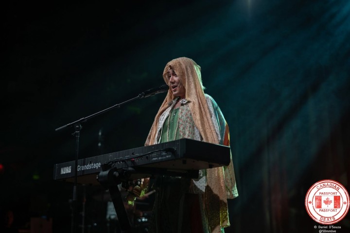 Fujii Kaze singing behind a Korg Grandstage keyboard with a draped head covering at HISTORY in Toronto in August 2025.